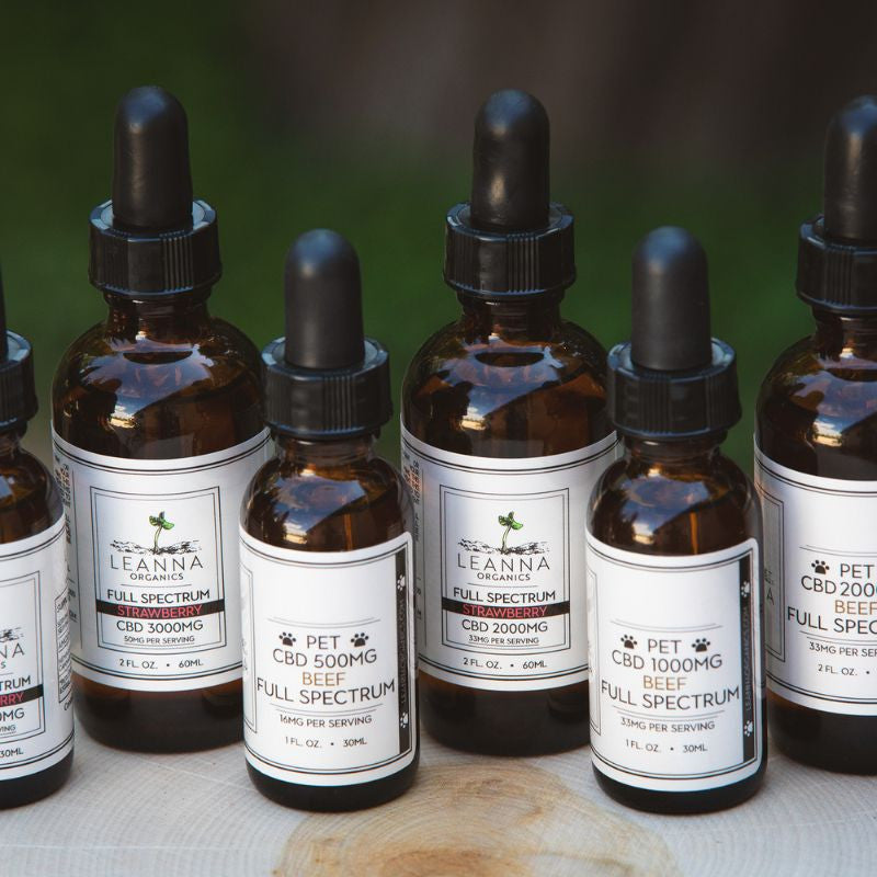 Row of CBD oil bottles with droppers on a wooden surface