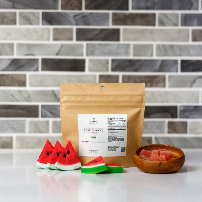 CBD gummy package with watermelon slices and a wooden bowl on a tiled countertop
